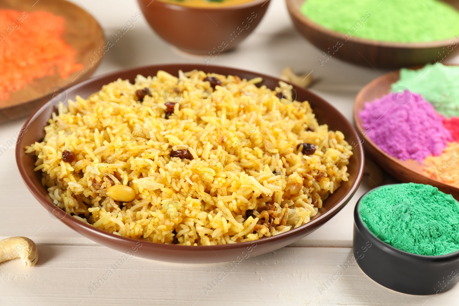 Photo of Traditional Indian food and color powders on white wooden table. Holi festival celebration