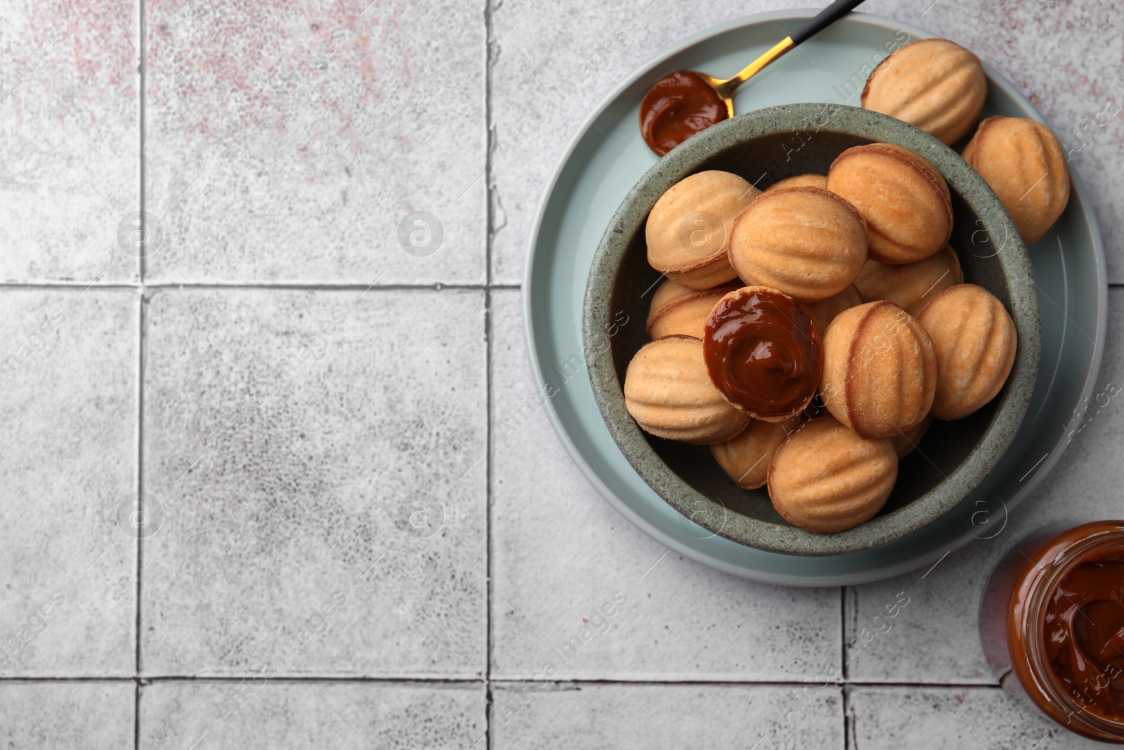 Photo of Delicious nut shaped cookies with boiled condensed milk on light textured table, flat lay. Space for text