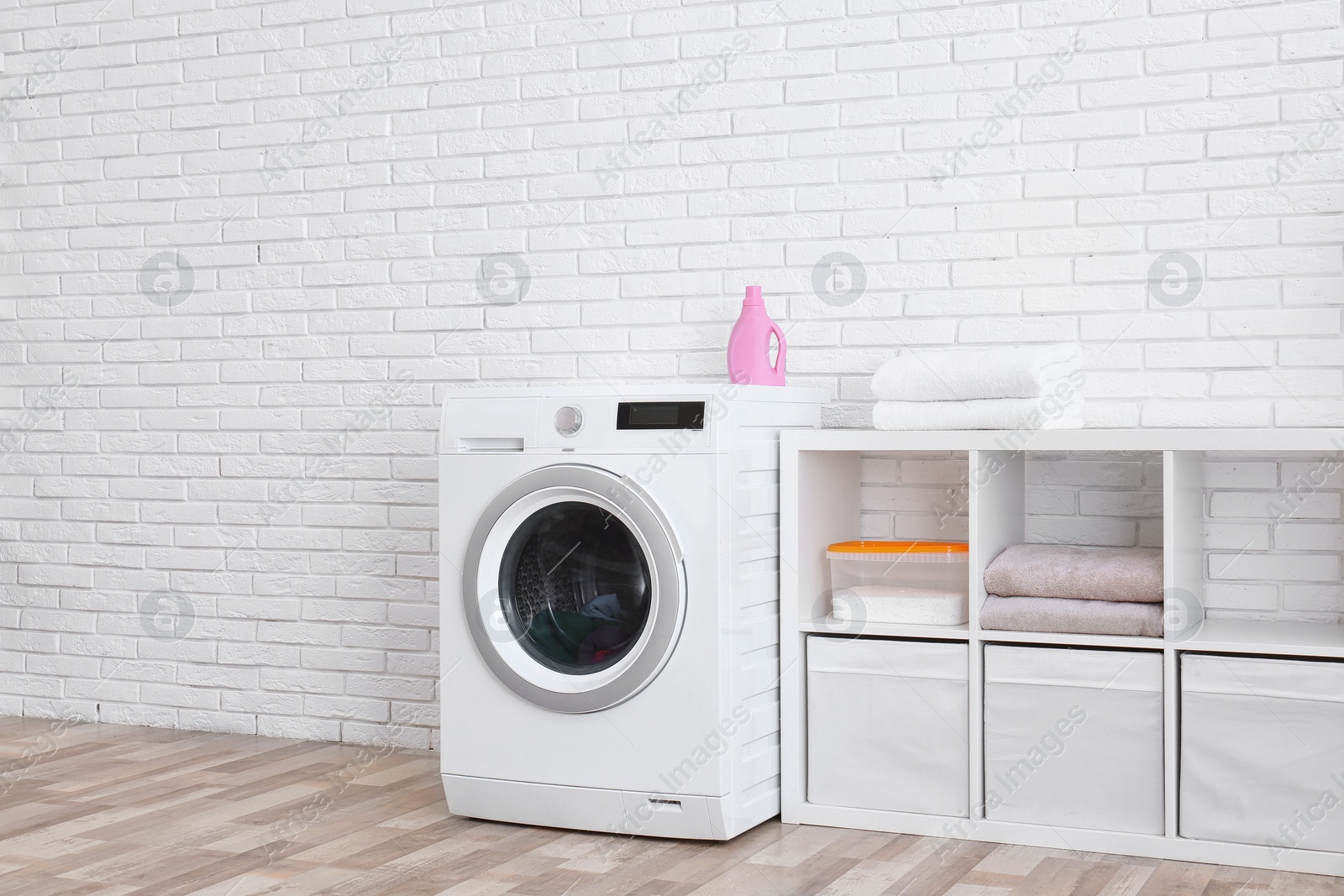 Photo of Modern washing machine near brick wall in laundry room interior, space for text