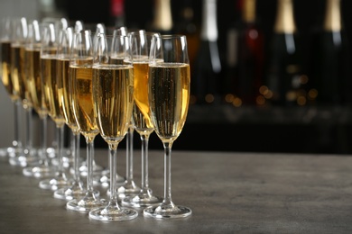 Photo of Glasses of champagne on table against blurred background. Space for text