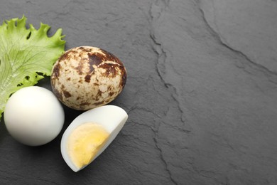 Unpeeled and peeled hard boiled quail eggs with lettuce leaf on black table, flat lay. Space for text