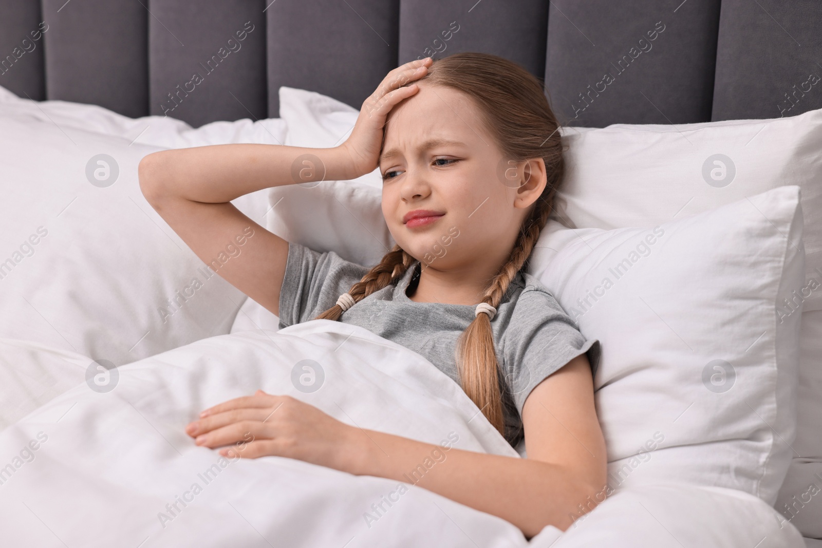 Photo of Little girl suffering from headache in bed