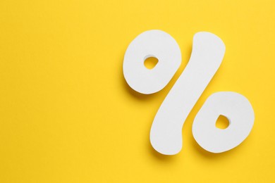 Photo of White percent sign on yellow background, flat lay. Space for text