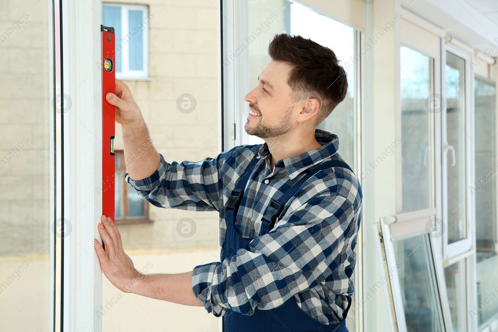 Photo of Construction worker using bubble level while installing window indoors