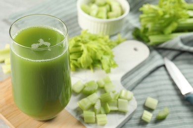 Glass of delicious celery juice and vegetables on wooden board, closeup. Space for text