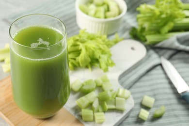 Photo of Glass of delicious celery juice and vegetables on wooden board, closeup. Space for text