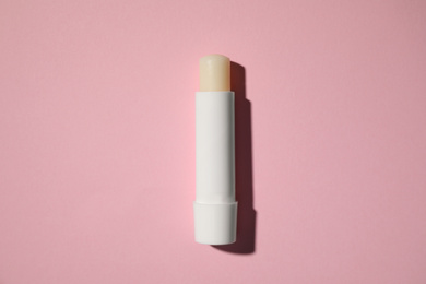 Photo of Hygienic lipstick on pink background, top view