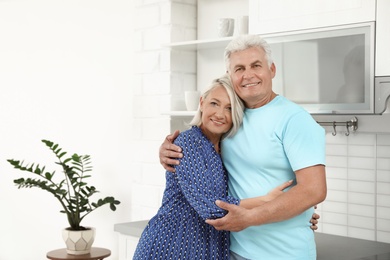 Photo of Portrait of affectionate senior couple in kitchen. Space for text