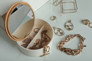 Photo of Jewelry box with mirror and stylish golden bijouterie on table
