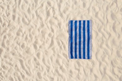 Image of Striped beach towel on sand, aerial view. Space for text