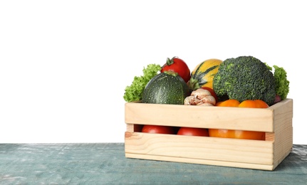 Photo of Wooden crate full of delicious fresh vegetables on table against white background