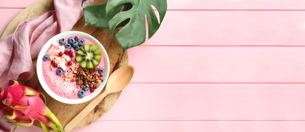Image of Smoothie bowl with granola, kiwi and berries on pink wooden table, top view. Banner design with space for text