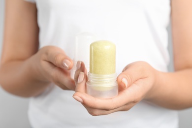 Photo of Young woman holding natural crystal alum stick deodorant, closeup