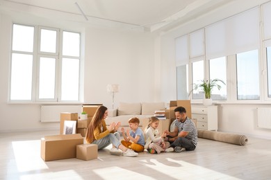 Photo of Happy family playing on floor in new apartment. Moving day