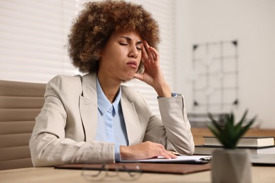 Photo of Woman suffering from headache at workplace in office