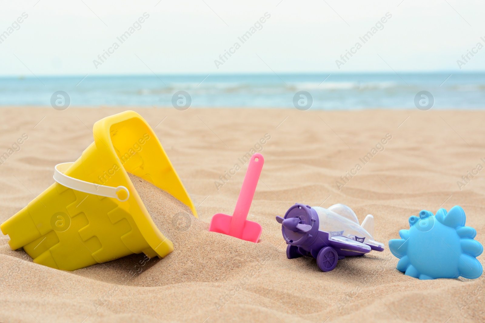 Photo of Set of colorful beach toys on sand near sea
