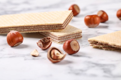 Delicious wafers with hazelnuts on marble background, closeup