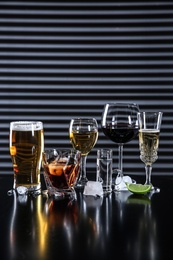 Many different alcoholic drinks on table against dark background. Space for text