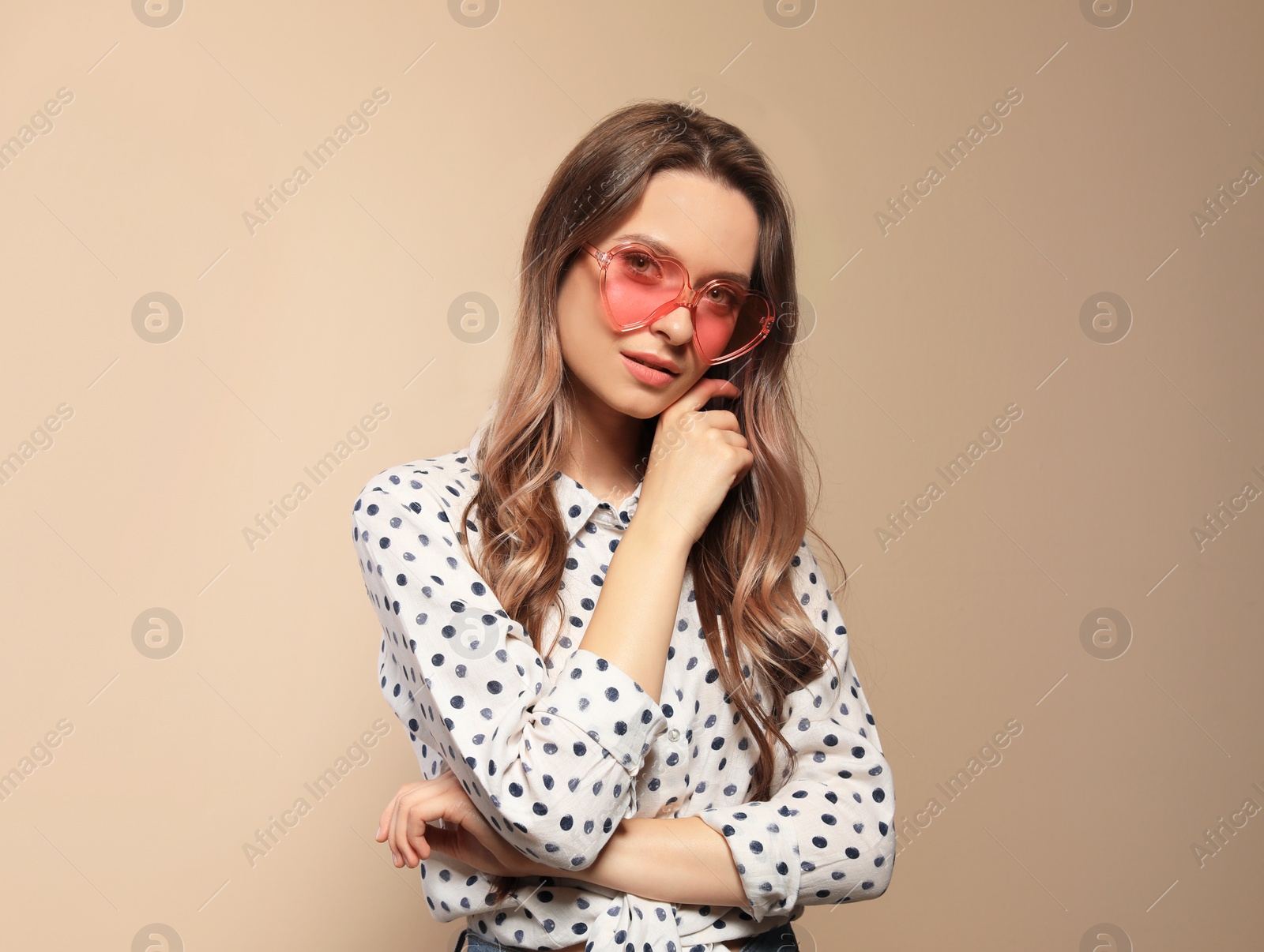 Photo of Portrait of beautiful young woman with heart shaped sunglasses on color background