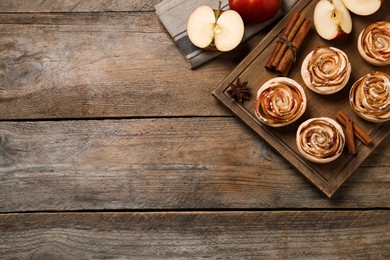 Photo of Freshly baked apple roses on wooden table, flat lay. Space for text