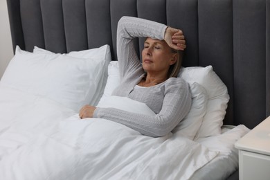Photo of Menopause. Woman suffering from headache in bed indoors