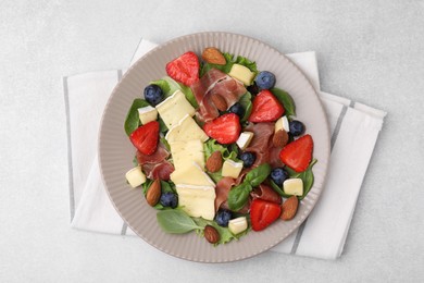 Photo of Tasty salad with brie cheese, prosciutto, almonds and berries on light grey table, top view