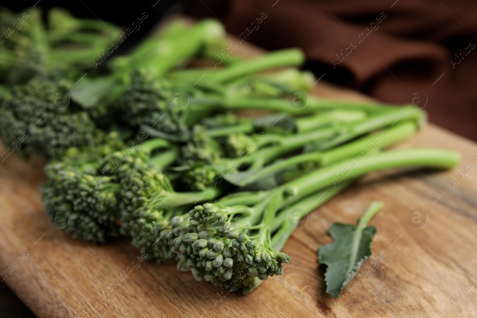 Photo of Fresh raw broccolini on wooden board, closeup. Healthy food