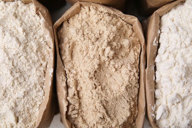 Paper sacks with different types of flour as background, closeup