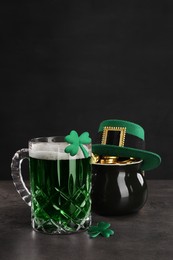 St. Patrick's day celebration. Green beer, leprechaun hat, pot of gold and decorative clover leaves on grey table. Space for text