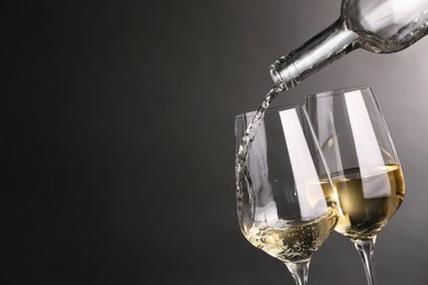 Pouring white wine into glass against grey background, closeup. Space for text