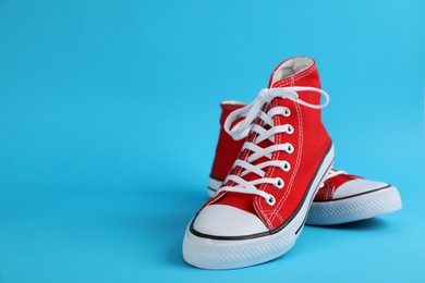 Photo of Pair of stylish sneakers on light blue background, space for text