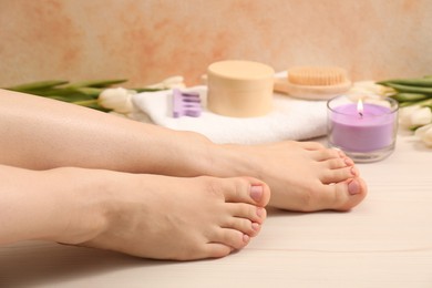 Photo of Woman with neat toenails after pedicure procedure on wooden floor, closeup
