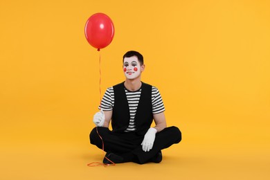 Photo of Funny mime artist with balloon on orange background