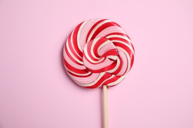 Stick with colorful lollipop swirl on pink background, top view