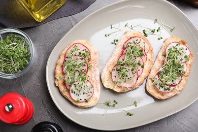 Delicious sandwiches with radish, cheese and microgreens on grey table, flat lay