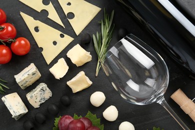 Tasty red wine and snacks on black table, flat lay