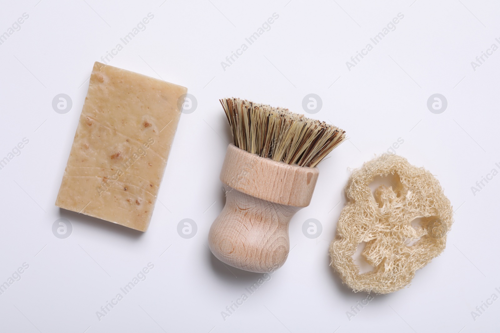 Photo of Cleaning brush, soap bar and loofah on white background, flat lay