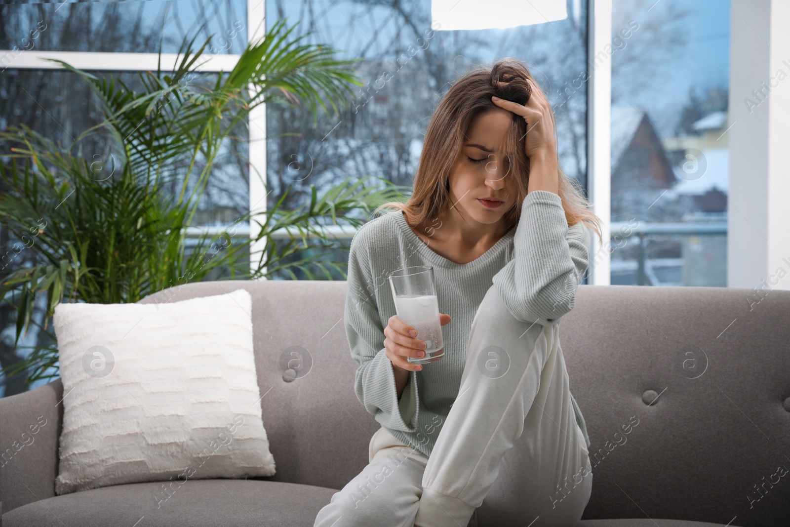 Photo of Woman holding glass of medicine for hangover at home