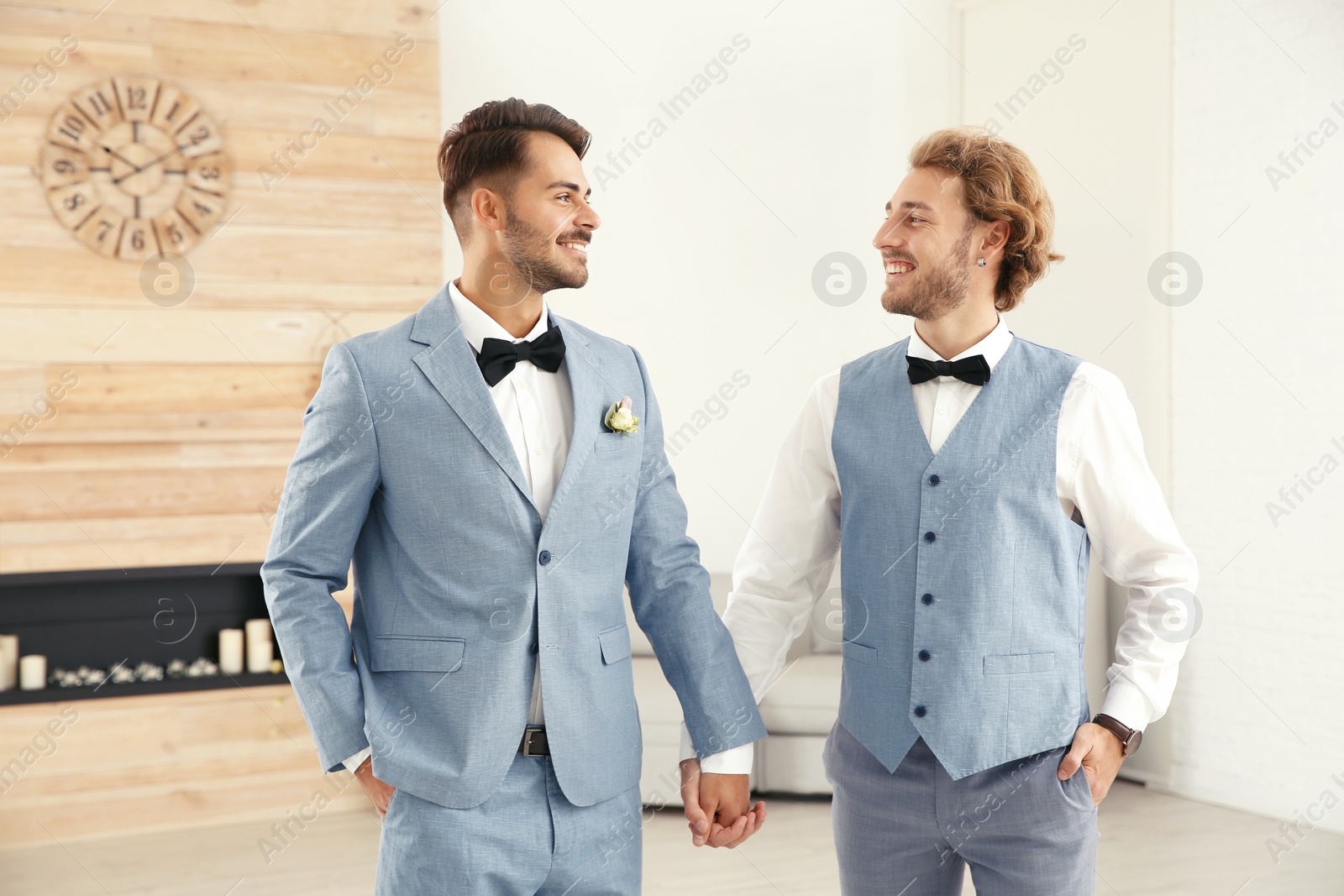 Photo of Happy newlywed gay couple in suits at home