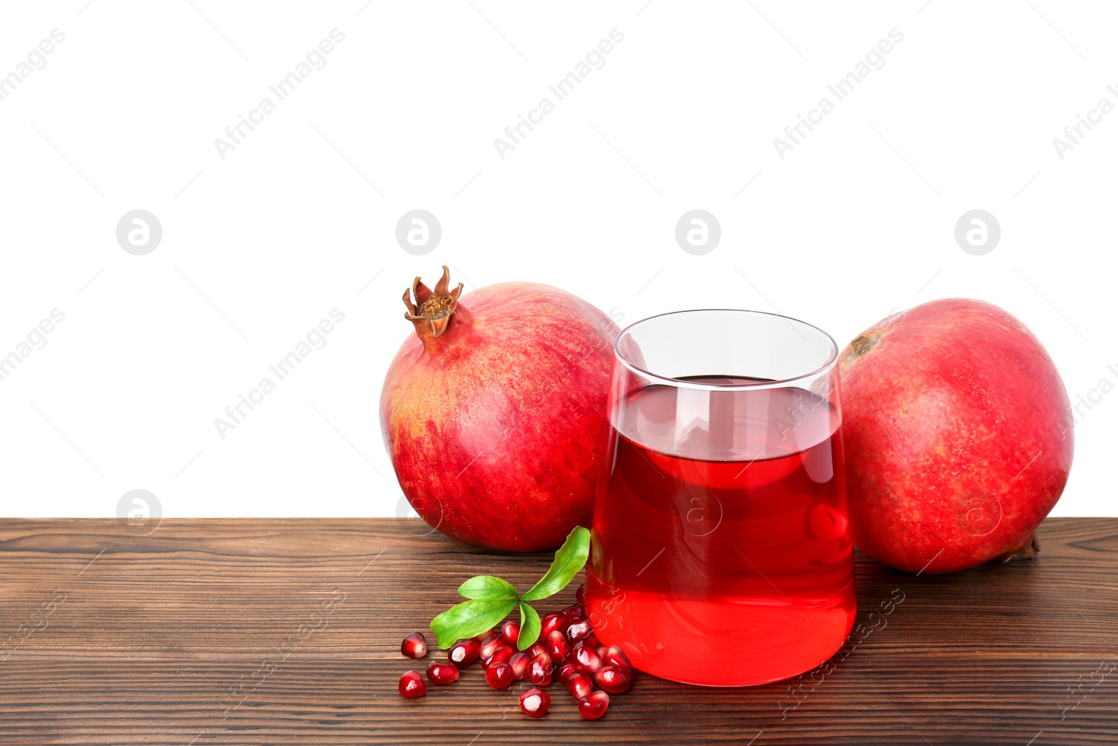 Photo of Refreshing pomegranate juice in glass, leaves and fruits on wooden table against white background. Space for text