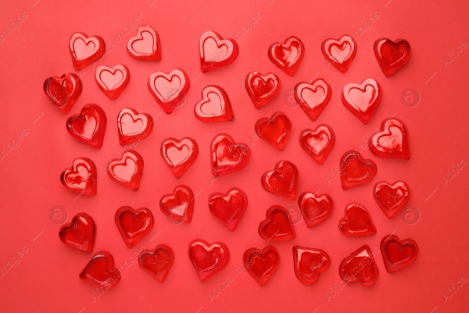 Photo of Many heart shaped jelly candies on red background, flat lay