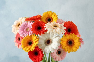 Photo of Bouquet of beautiful colorful gerbera flowers on light blue background