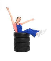 Female mechanic in uniform with car tires on white background