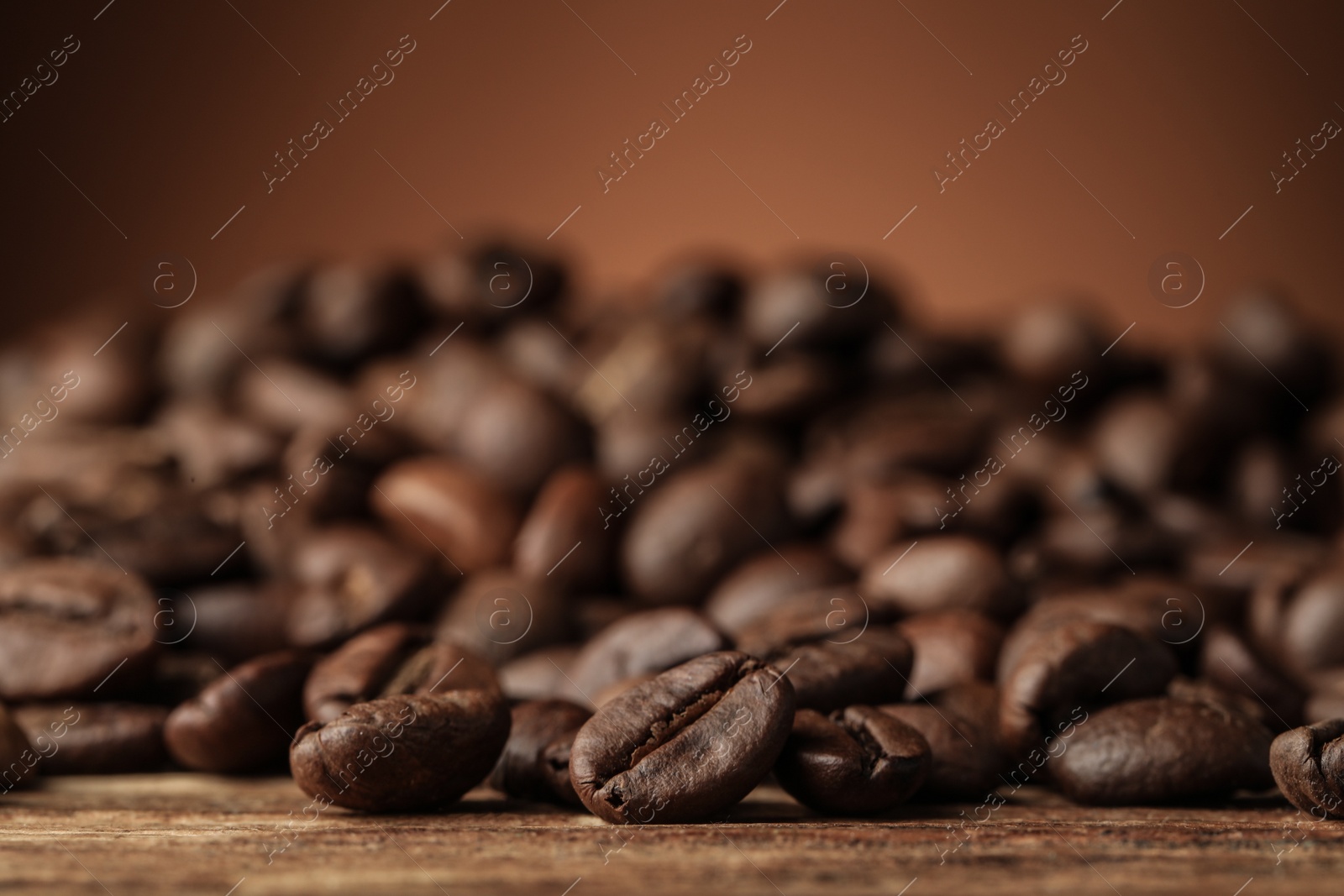 Photo of Many roasted coffee beans on wooden table, closeup