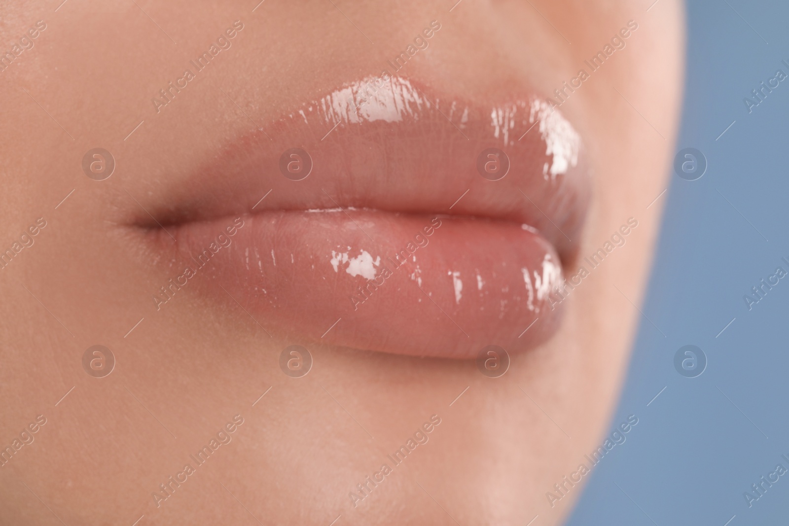 Photo of Young woman with beautiful full lips on light blue background, closeup