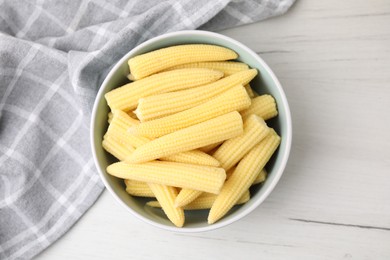 Photo of Tasty fresh yellow baby corns in bowl on white wooden table, top view