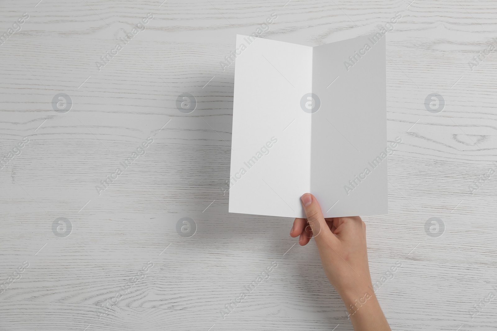 Photo of Woman with blank brochure on wooden background, above view. Mock up for design