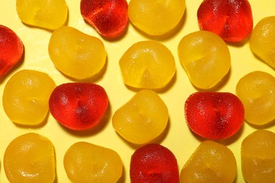 Delicious gummy cherry candies on yellow background, flat lay