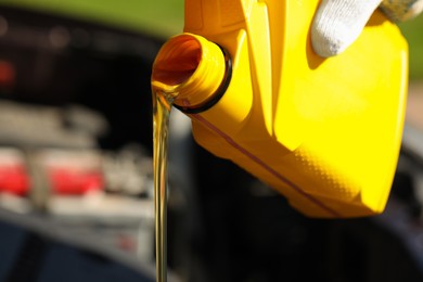 Photo of Man pouring motor oil from yellow container, closeup. Space for text