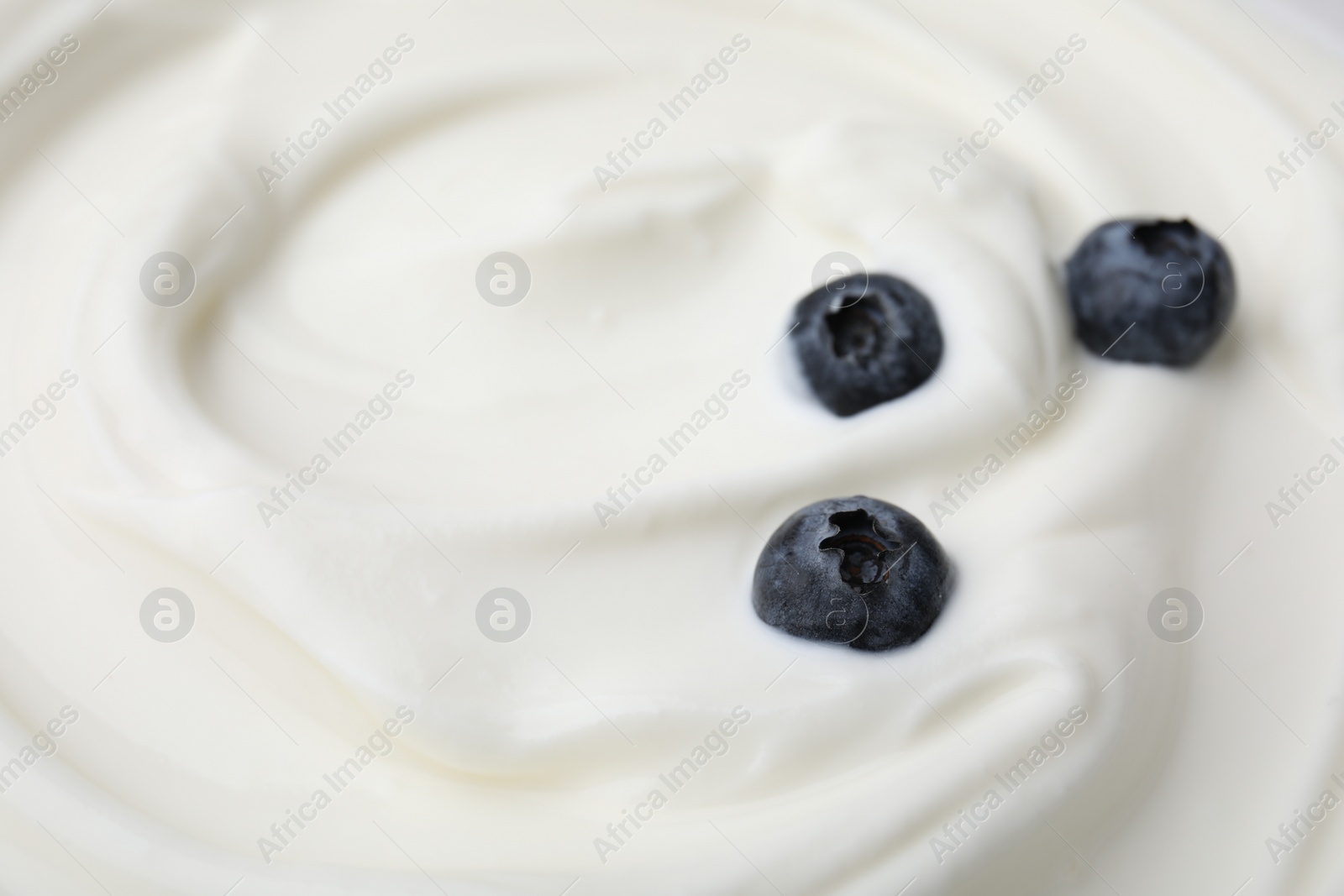 Photo of Tasty yogurt with blueberries as background, closeup. Space for text